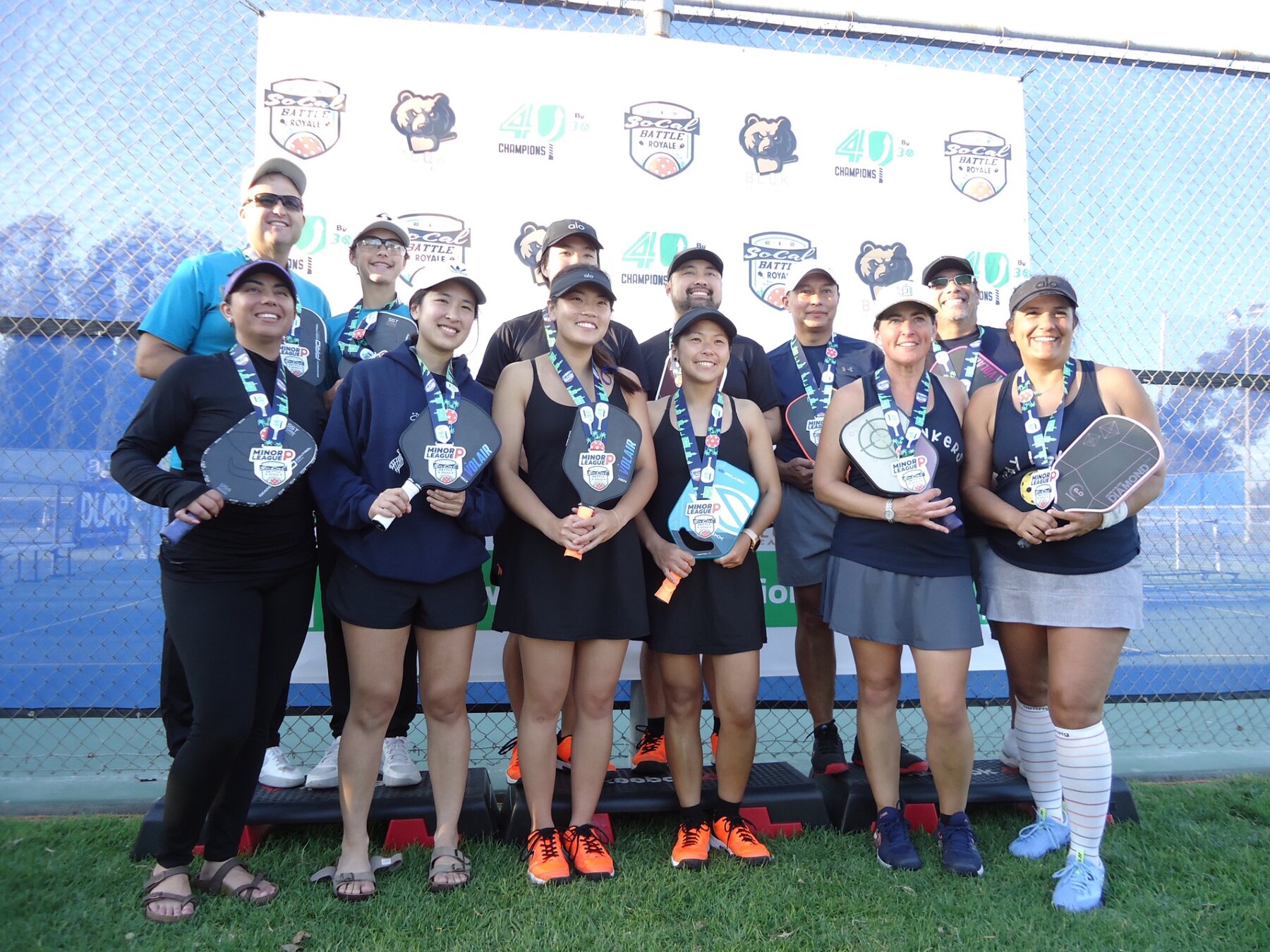 Mixed team celebrating medals together at a community pickleball tournament