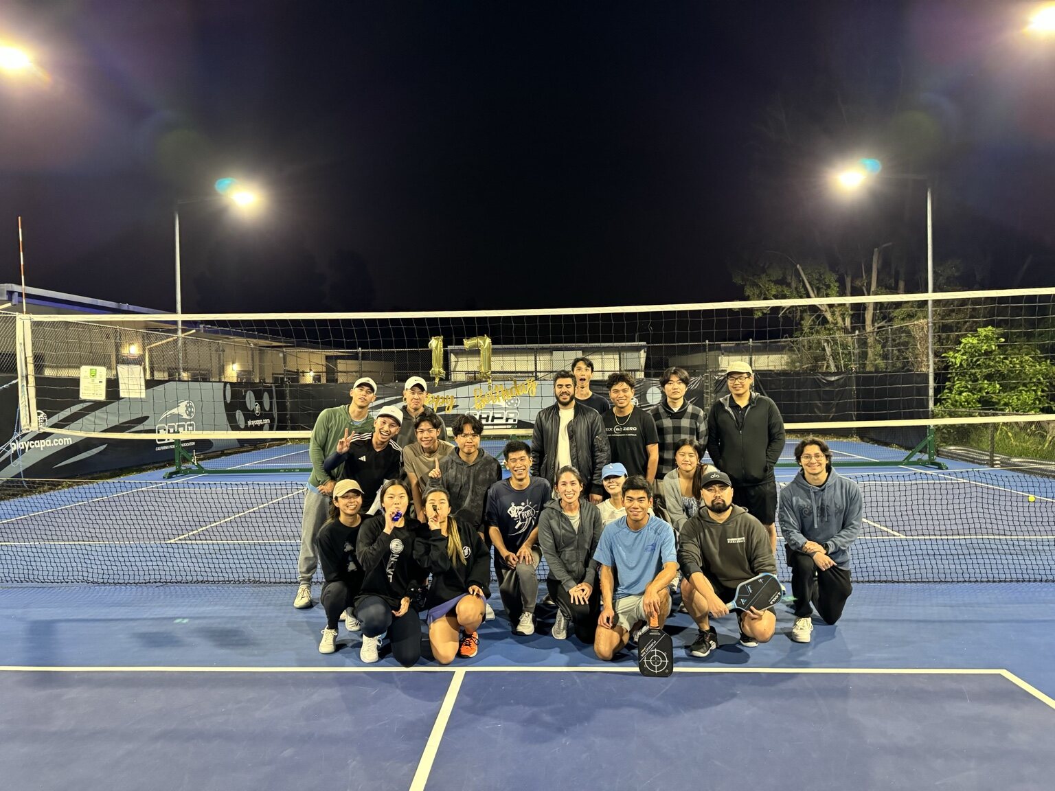 Players celebrating together at a nighttime pickleball event